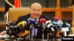 Yemen's President Abd-Rabbu Mansour Hadi speaks as he holds an agreement (L) signed between the government and Houthi rebels, in Sanaa, Sept. 21, 2014.