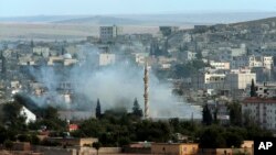 Asap mengepul dari kota Kobani akibat pertempuran antara pejuang Kurdi melawan militan ISIS (19/10).