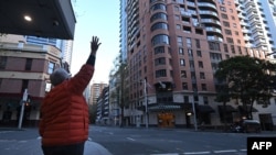 A woman waves to her family members in quarantine at a hotel in Sydney, July 17, 2021, after authorities ordered new restrictions as a weekslong lockdown failed to quash an outbreak of COVID-19 infections.