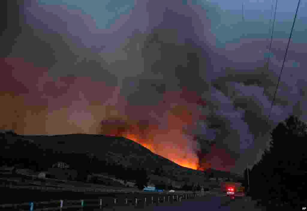 Kendaraan darurat melewati Twisp River Road saat kebakaran hutan berkobar di perbukitan wilayah Twisp, Washington (19/8). (AP/Ted S. Warren)