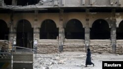 FILE - A woman walks at a damaged site after an airstrike in Douma, Eastern Ghouta, a suburb of Damascus, Syria, Nov. 2, 2017.