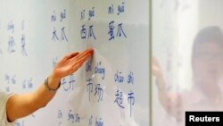 FILE - An instructor points out Mandarin characters on a whiteboard at a night class for people learning Mandarin as a second language in Singapore, Sept. 1, 2009.