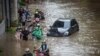 Warga mendorong sepeda motornya melewati air di daerah terdampak banjir menyusul hujan deras di Jakarta, 20 Februari 2021. (Foto: Antara/Aprillio Akbar via REUTERS)