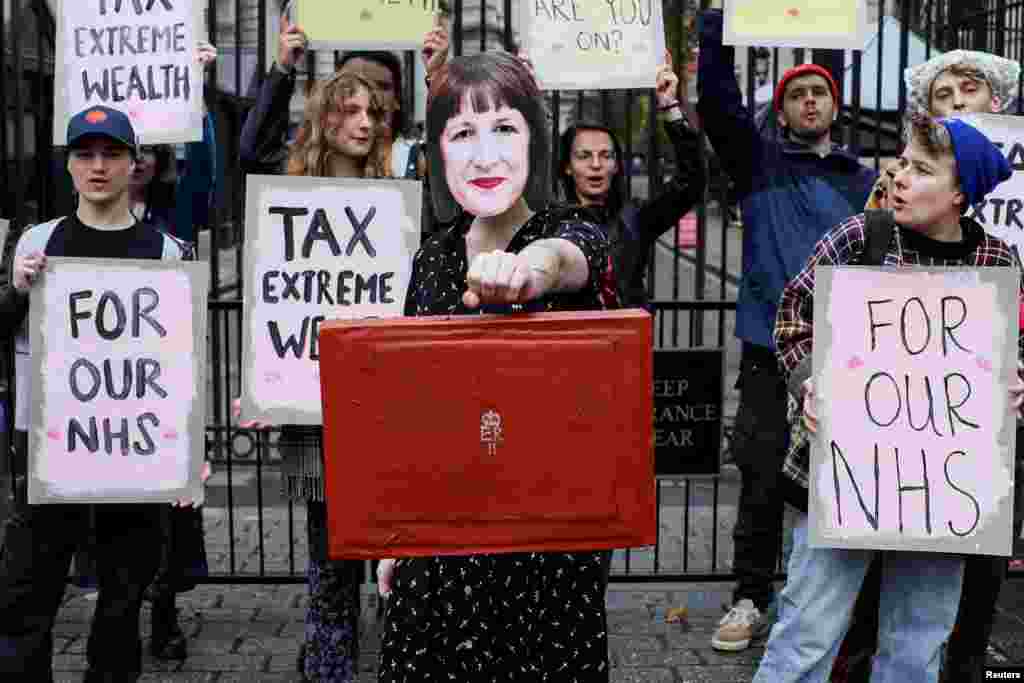 A demonstrator holds a mock red budget box while wearing a mask representing Britain&#39;s Chancellor of the Exchequer Rachel Reeves, during a protest outside Downing Street in London, Britain.