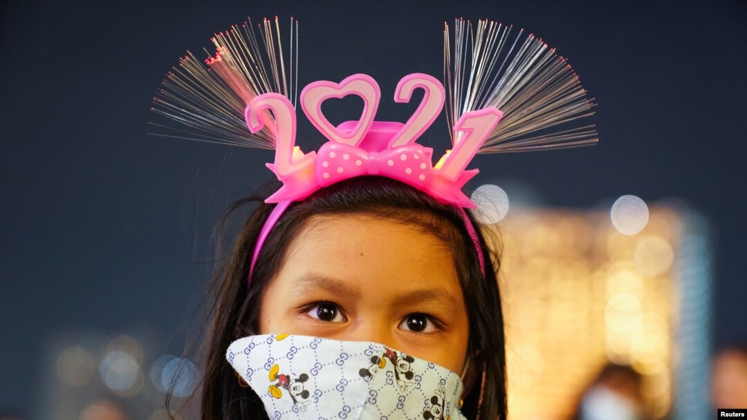 Una niña con una máscara y una banda para la cabeza "2021" visita un centro comercial en medio de la prohibición de las celebraciones de la cuenta regresiva del Año Nuevo por coronavirus. Bangkok, Tailandia, 31 de diciembre de 2020. [Reuters]