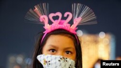 Una niña con una máscara y una banda para la cabeza "2021" visita un centro comercial en medio de la prohibición de las celebraciones de la cuenta regresiva del Año Nuevo por coronavirus. Bangkok, Tailandia, 31 de diciembre de 2020. [Reuters]