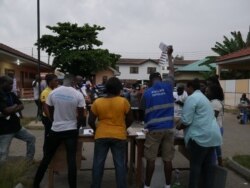 Voters watch on at a station in Accra as votes are compiled, Dec 7, 2020. (Stacey Knott/VOA)