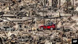 A car drives past homes and vehicles destroyed by the Palisades Fire at the Pacific Palisades Bowl Mobile Estates on Jan. 12, 2025, in Los Angeles. 