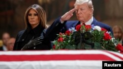 US President Donald J. Trump, with First Lady Melania Trump, salutes the casket containing the body of former US President George H.W. Bush in the Rotunda of the US Capitol in Washington, DC, December 3, 2018. 