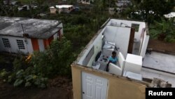Ernestina Lebron looks at her refrigerator while standing in her home, after Hurricane Maria hit the island in September 2017, in Maunabo, Puerto Rico, Jan. 27, 2018. 