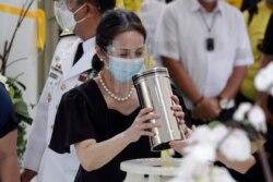 Ballsy Aquino-Cruz holds the urn of her brother former Philippine President Benigno Aquino III before he is placed on the tomb on June 26, 2021 at a memorial park in suburban Paranaque city, Philippines.