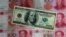 FILE - A photo illustration shows a $100 banknote placed above Chinese 100 yuan banknotes in Beijing. 