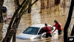 Trabajadores de búsqueda y rescate revisan un auto atrapado en una inundación luego de que fuertes lluvias provocaron que el río Guadalupe se desborde, el domingo 4 de febrero de 2024, en San José, California.