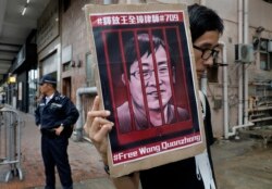 FILE - A protester holds a picture of imprisoned and prominent Chinese human rights lawyer Wang Quanzhang during a protest outside the Chinese liaison office in Hong Kong, July 13, 2018.