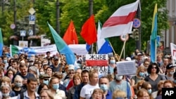 People carrying a poster reading "Long Live Belarus", and an old Belarusian national flag, march during an unsanctioned protest in support of Sergei Furgal, the governor of the Khabarovsk region, Russia, Aug. 15, 2020. 