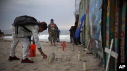 FILE- Candles are placed next to the border fence that separates Mexico from the U.S., in memory of migrants who have died during their journey toward the U.S., in Tijuana, Mexico, June 29, 2019. 