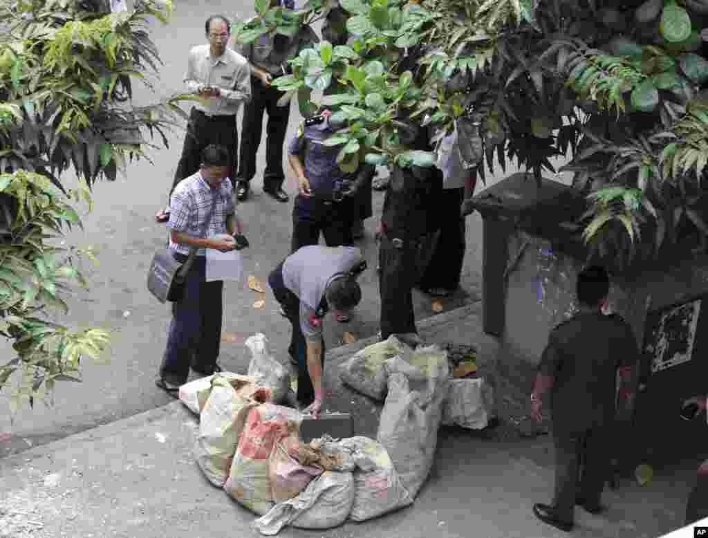 A police officer takes a close look after a bomb squad found a suspicious looking package in downtown Rangoon, Burma, Oct. 15, 2013.