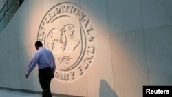 FILE — A man walks past the International Monetary Fund (IMF) logo at its headquarters in Washington, on May 10, 2018.