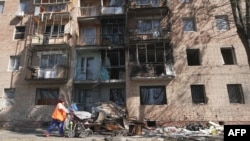 FILE - A woman walks past a building damaged by Ukrainian strikes in Kursk following Ukraine's offensive into Russia's western Kursk region, Aug. 16, 2024. Since Kyiv launched its cross-border assault into the Kursk region in August 2024, Moscow has been pushing back hard.