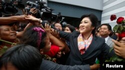 Thailand's Prime Minister Yingluck Shinawatra greets her supporters as she leaves the Permanent Secretary of Defence office in Bangkok May 7, 2014. A Thai court found Yingluck guilty of violating the constitution on Wednesday and said she had to step down