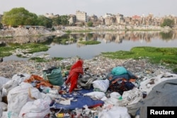Plastic waste floats in the Buriganga river while a woman sorts it for recycling in Dhaka, Bangladesh, April 21, 2024. (REUTERS/Mohammad Ponir Hossain/File Photo)