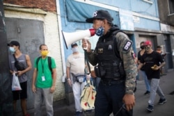 A member of the National Police Action Force uses a megaphone, telling people to return home due to the government-ordered lockdown to curb the spread of COVID-19, in Caracas, Venezuela, July 2, 2020.