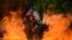 Seen through a burning street barricade, an anti-government demonstrator waves a Chilean flag in Santiago, Chile, Oct. 28, 2019.