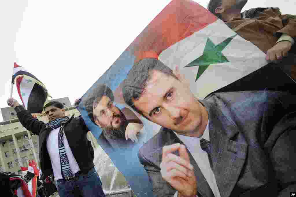 People wave Syrian flags and carry a poster depicting Syria's President Bashar al-Assad and Lebanon's Hezbollah Leader Sayyed Hassan Nasrallah during a rally to show support for al-Assad in Damascus, Syria, November 16, 2011. (Reuters)