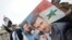 FILE - People wave Syrian flags and carry a poster depicting Syria's President Bashar al-Assad and Lebanon's Hezbollah Leader Sayyed Hassan Nasrallah during a rally to show support for al-Assad in Damascus, Syria.