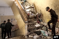 Men climb down a stairwell littered with rubble and debris in a school hit by Israeli bombardment in Nuseirat, central Gaza Strip, on Oct. 24, 2024.