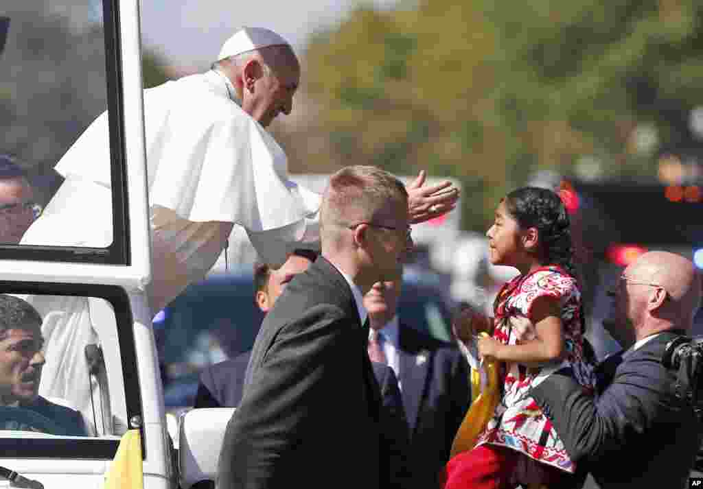 Paus Fransiskus mengulurkan tangannya dari dalam mobil kepada seorang anak dalam parade di Washington (23/9). (AP/Alex Brandon, Pool)