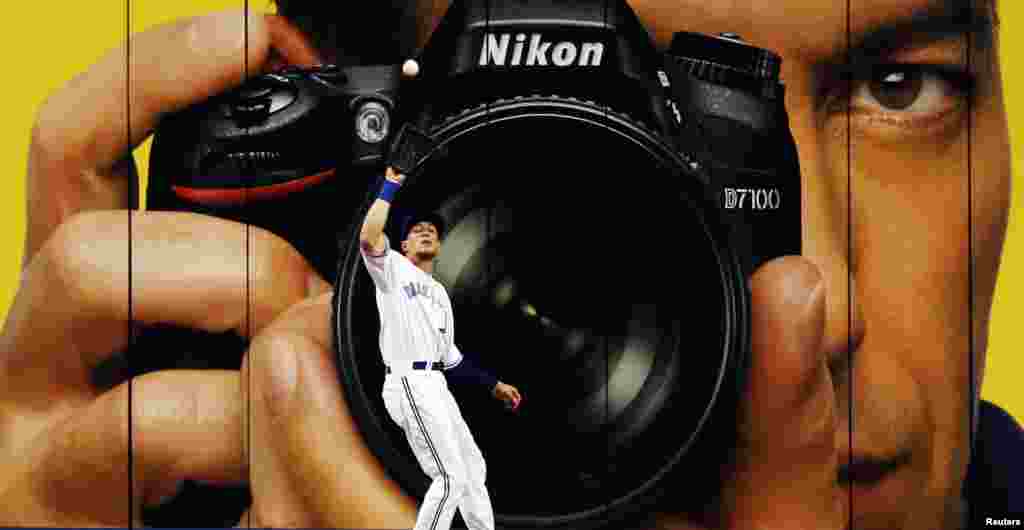 Pemain baseball klub Toronto Blue Jays, Colby Rasmus menangkap bola di depan kamera iklan raksasa selama pertandingan baseball, di Toronto, Kanada.