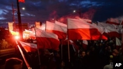 Manifestantes queman luces de bengala y ondean banderas polacas en una marcha anual para conemorar el Día Nacional de la Independencia, en Varsovia, Polonia, el 11 de noviembre de 2017.