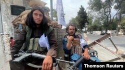 塔利班成员坐在喀布尔的一个检查站。
