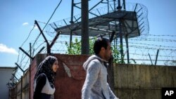 Illegal migrants walk toward the city center next to the fence around the refugee camp in Debrecen, 221 kms from Budapest, July 1, 2015.