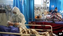 A medic treats a patient infected with the new coronavirus, at a hospital in Tehran, Iran, Sunday, March 8, 2020. 