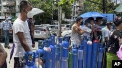 People queue with their oxygen tanks outside an oxygen refill station in Pazundaung township in Yangon, Myanmar, July 11, 2021.