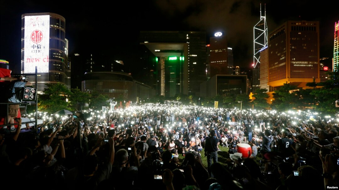 Pro-democracy protesters switch on their mobile phones during a campaign to kick off the Occupy Central civil disobedience event in front of the financial Central district in Hong Kong, Aug. 31, 2014.