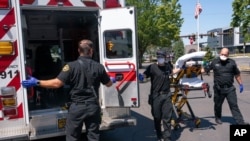 Salem Fire Department paramedics and employees of Falck Northwest ambulances respond to a heat exposure call during a heat wave, June 26, 2021, in Salem, Ore. 