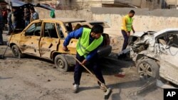 Para pekerja pemerintah daerah setempat tengah membersihkan lokasi serangan bom di dekat Universitas teknologi di jalan Sina, pusat kota Baghdad (15/1).