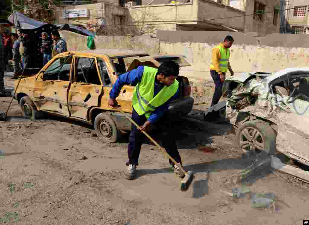 Municipality workers clean up after a car bomb attack near the Technology University on Sinaa Street in downtown Baghdad, Jan. 15, 2014.