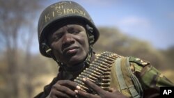 A Kenyan army soldier wears a helmet on which is written in Kiswahili "Tea in Kismayo", referring to a key strategic Somali town then under the control of al-Shabab, checks his ammunition belt near the town of Dhobley, in Somalia.