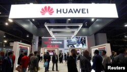 FILE - Attendees pass by a Huawei booth during the 2019 CES in Las Vegas, Nevada, U.S. Jan. 9, 2019. 