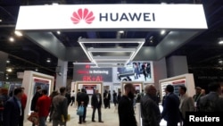 FILE - Attendees pass by a Huawei booth during the 2019 CES in Las Vegas, Nevada, U.S. Jan. 9, 2019. 