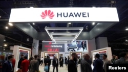 FILE - Attendees pass by a Huawei booth during the 2019 CES in Las Vegas, Nevada, Jan. 9, 2019. 