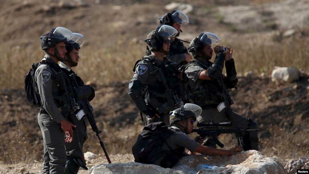 Seorang polisi perbatasan Israel membidik senjatanya ke warga Palestina dalam bentrokan dengan warga Palestina di titik pemeriksaan Hawara, Israel dekat kota Tepi Barat Nablus, 16 Oktober 2015. (REUTERS/Ahmad Talat)