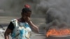 在海地总理阿里尔·亨利辞职后举行的示威活动中，一名妇女走过燃烧的轮胎。（2024年3月12日）