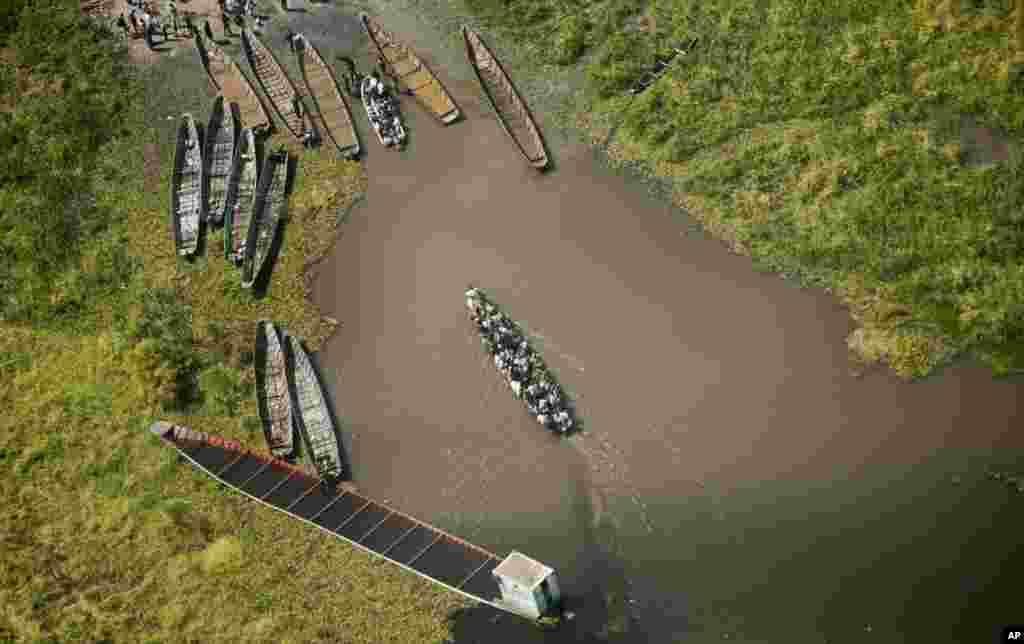 A pirogue packed with passengers arrives at a dock after crossing a waterway near the town of Malakal, seen from an airplane over South Sudan, Dec. 30, 2013. Around 200 people drowned Sunday when a boat carrying them away from the fighting in Malakal sank on Sunday, Jan. 12, 2014.