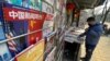 A newsstand vendor looks through his display near a magazine with a cover depicting U.S. President Joe Biden near U.S. and Chinese flags in Beijing on Jan. 21, 2021.