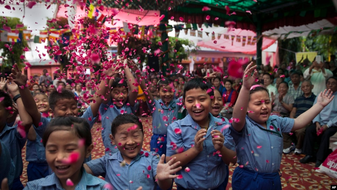 Exiled Tibetan school children throw flowers in the air as they sing a birthday song to celebrate their spiritual leader, the Dalai Lama's' 80th birthday in New Delhi, India, July 6, 2015.